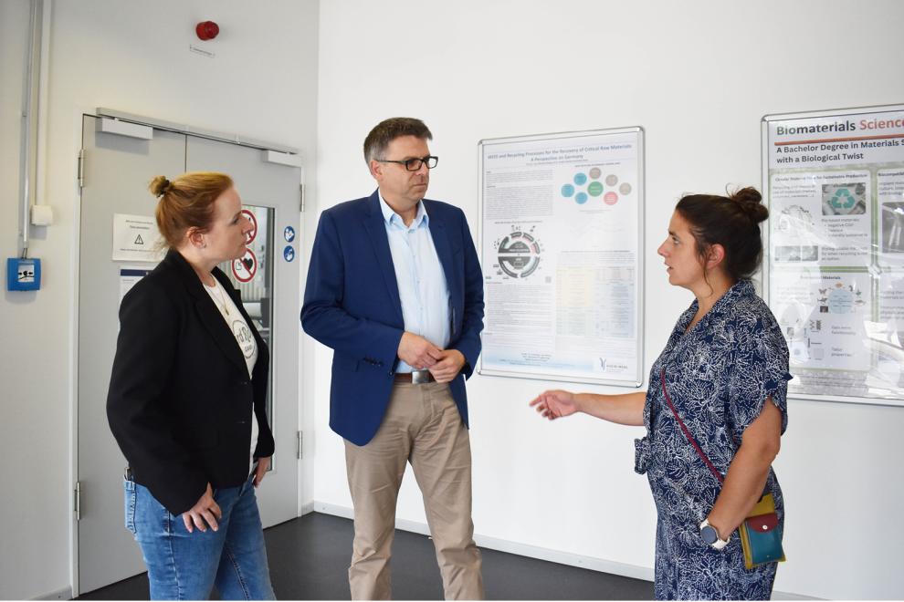 Der Präsident der HSRW steht mittig zwischen zwei Mitarbeiterinnen. Sie sind im Gespräch. 